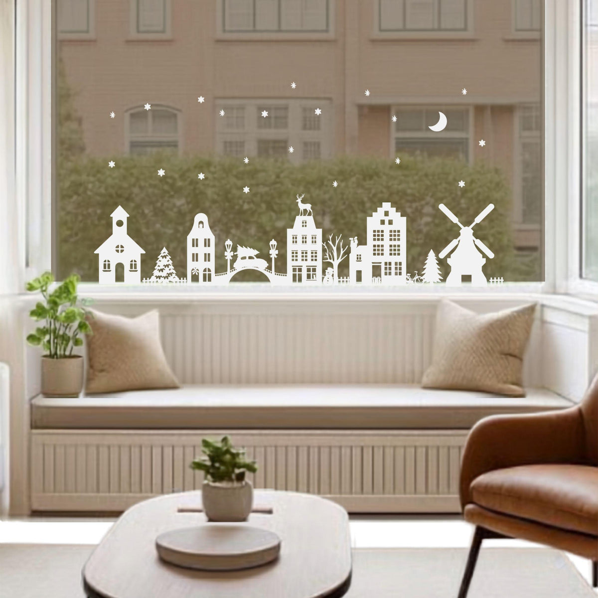 Witte statische raamstickers van een Kerstdorp met huisjes, molen, brug, kerk en Kerstbomen op een woonkamerraam van Studio DSigns