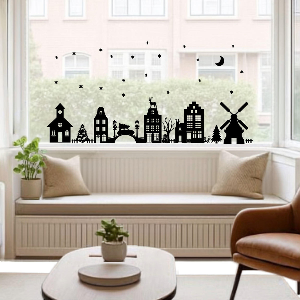 Zwarte statische raamstickers van een Kerstdorp met huisjes, molen, brug, kerk en kerstbomen op een woonkamerraam van Studio DSigns