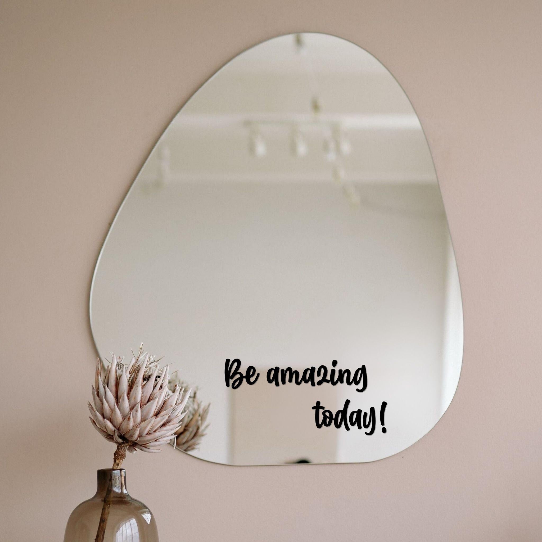 Zwarte spiegelsticker met tekst Be amazing today op een organische spiegel in een licht interieur met vaas en droogbloem