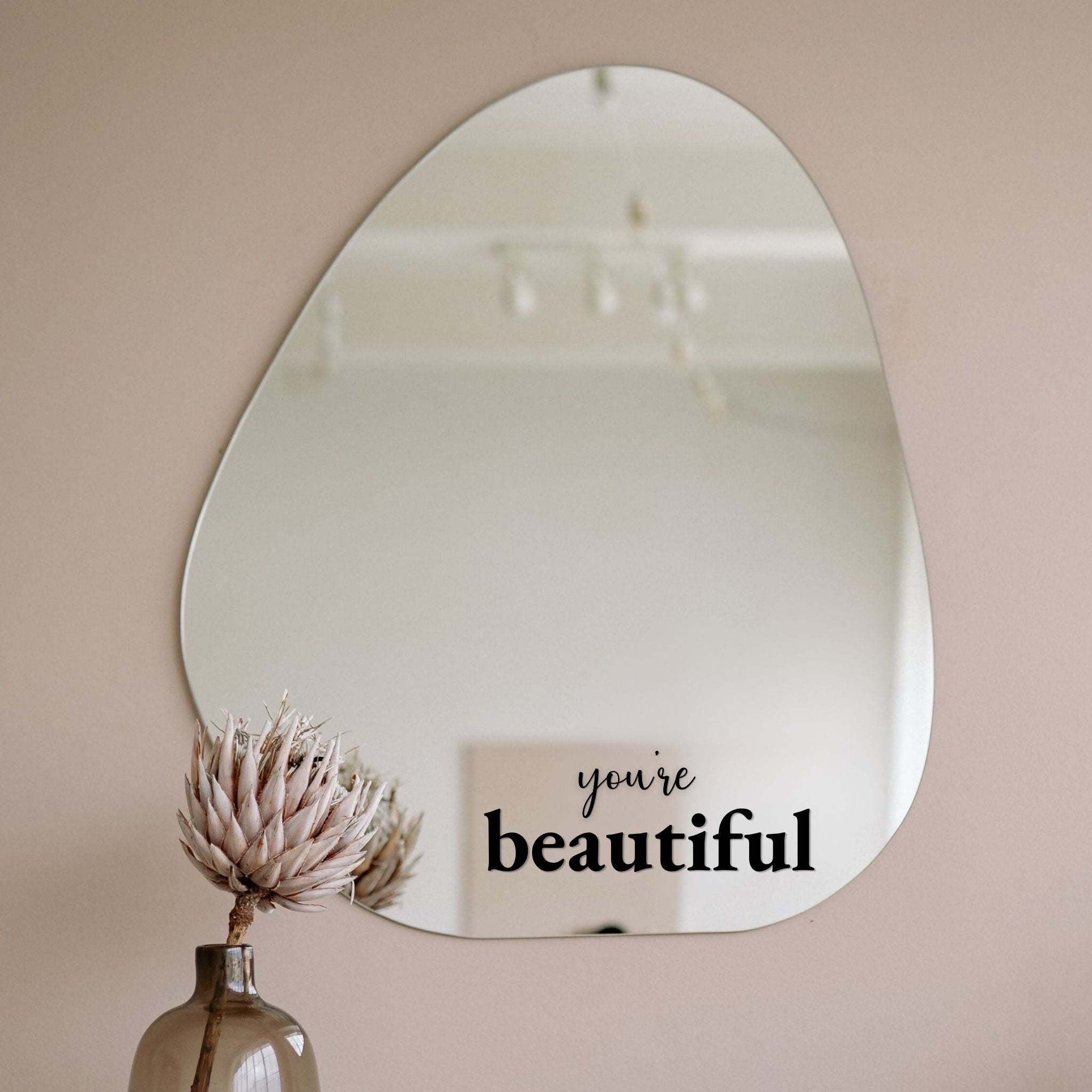 Zwarte spiegelsticker met tekst you're beautiful op organische wandspiegel in een rustig beige interieur