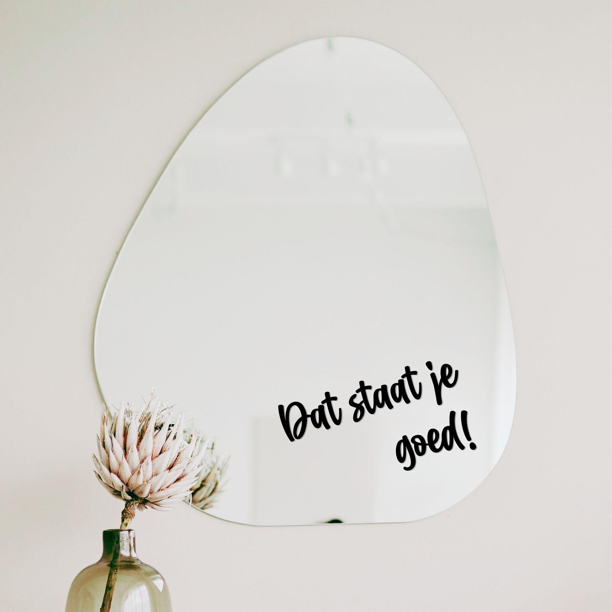 Zwarte spiegelsticker met tekst dat staat je goed op een organische spiegel in een licht interieur met vaas en droogbloem