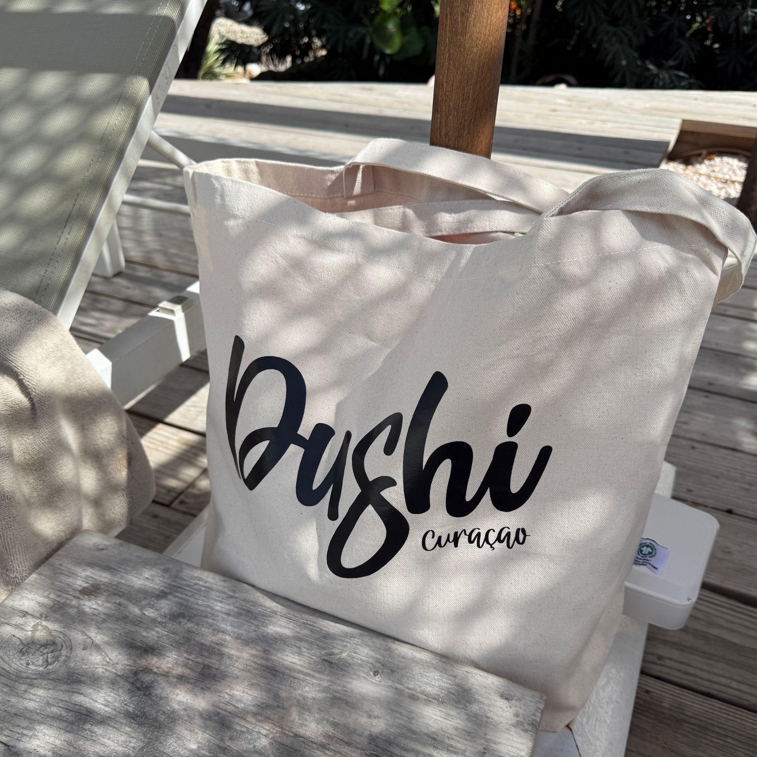 Ecru Dushi Curaçao strandtas op een ligbed in de schaduw.
