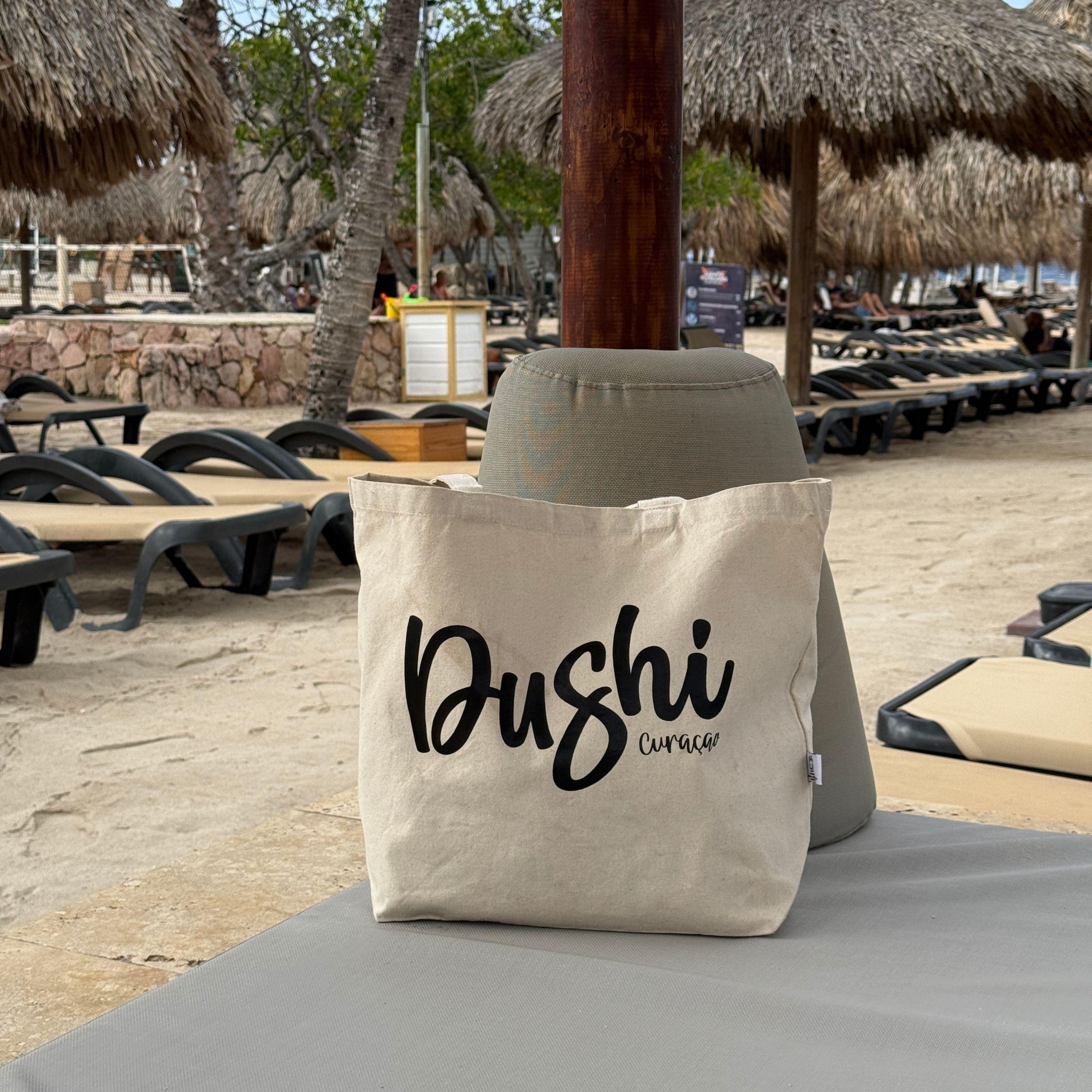 Dushi Curaçao strandtas op een ligbed op het strand van Curaçao.