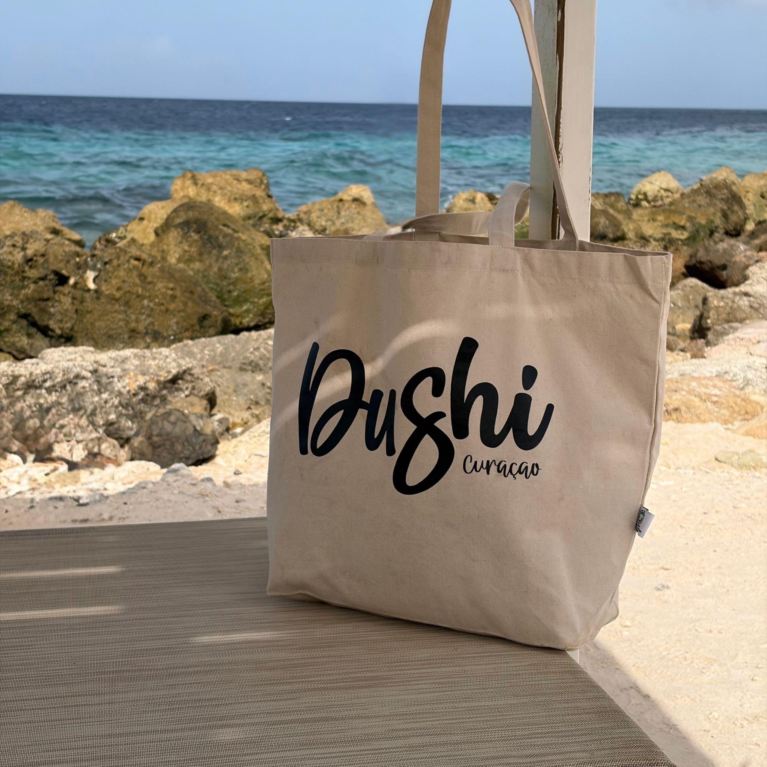 Dushi Curaçao strandtas op een ligbed met uitzicht op zee.