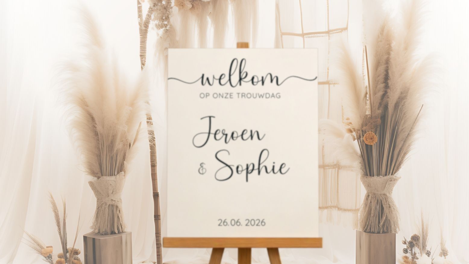 Welkomstbord voor een bruiloft met namen en datum, in boho stijl met pampasgras decoratie.